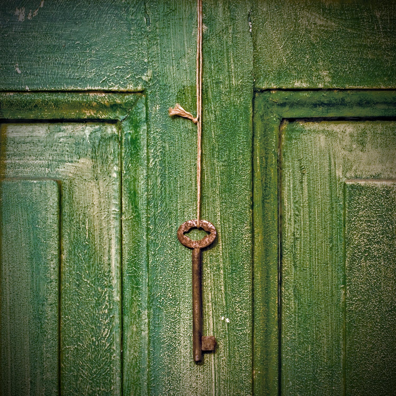 A weathered green door with an old key